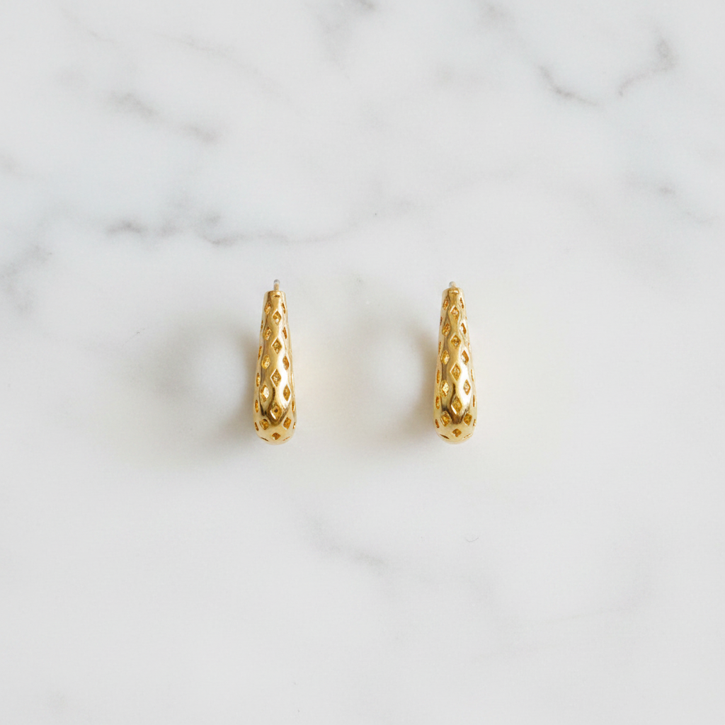 Tallulah gold filigree huggie hoop earrings flat lay on white marble