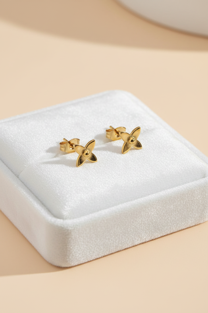 Oslo gold flower stud earrings on white velvet jewelry tray