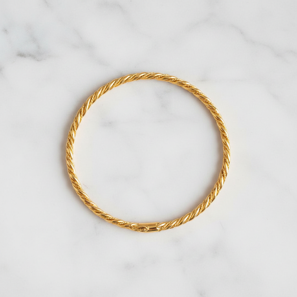 Langley slim closed gold twisted rope bangle flat lay on white marble