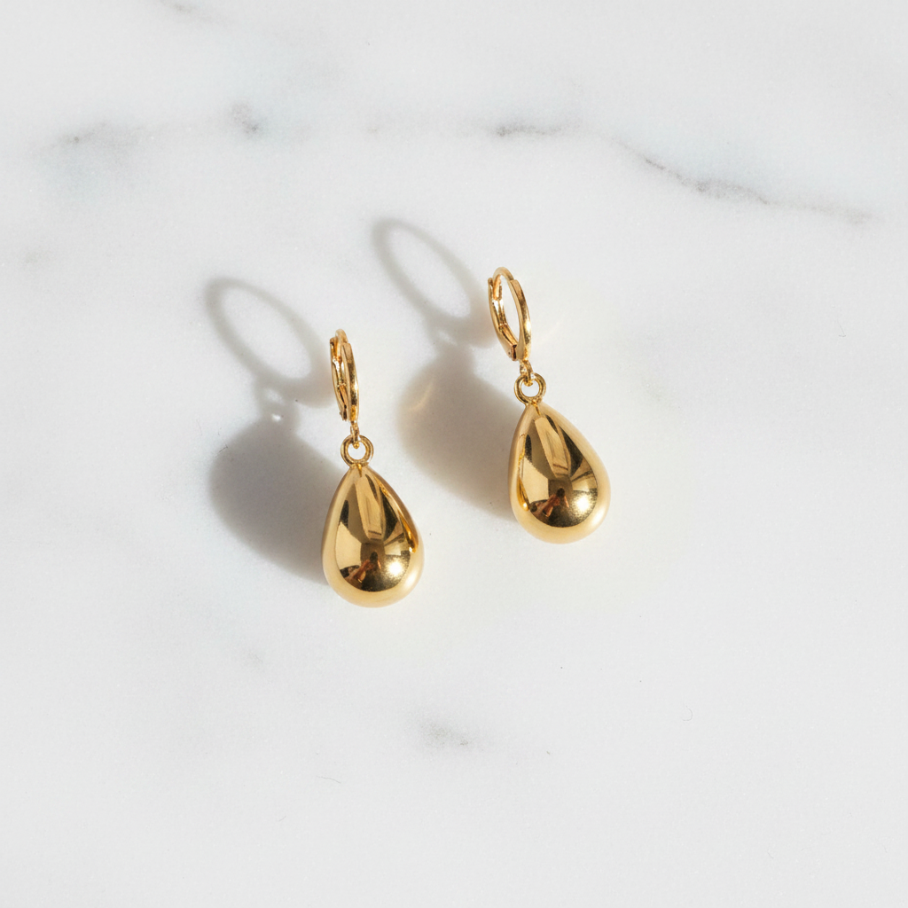 Winona polished gold teardrop dangle earrings flat lay on white marble