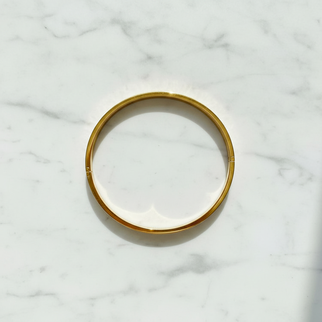 Anaya gold engraved bangle bracelet flat lay on white marble