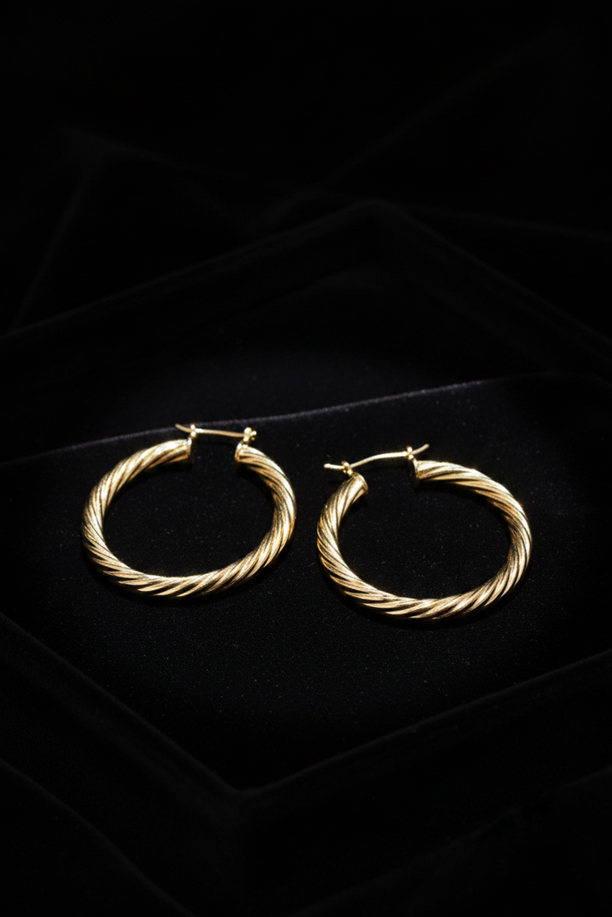 Efia gold twist hoop earrings on dark velvet jewelry tray