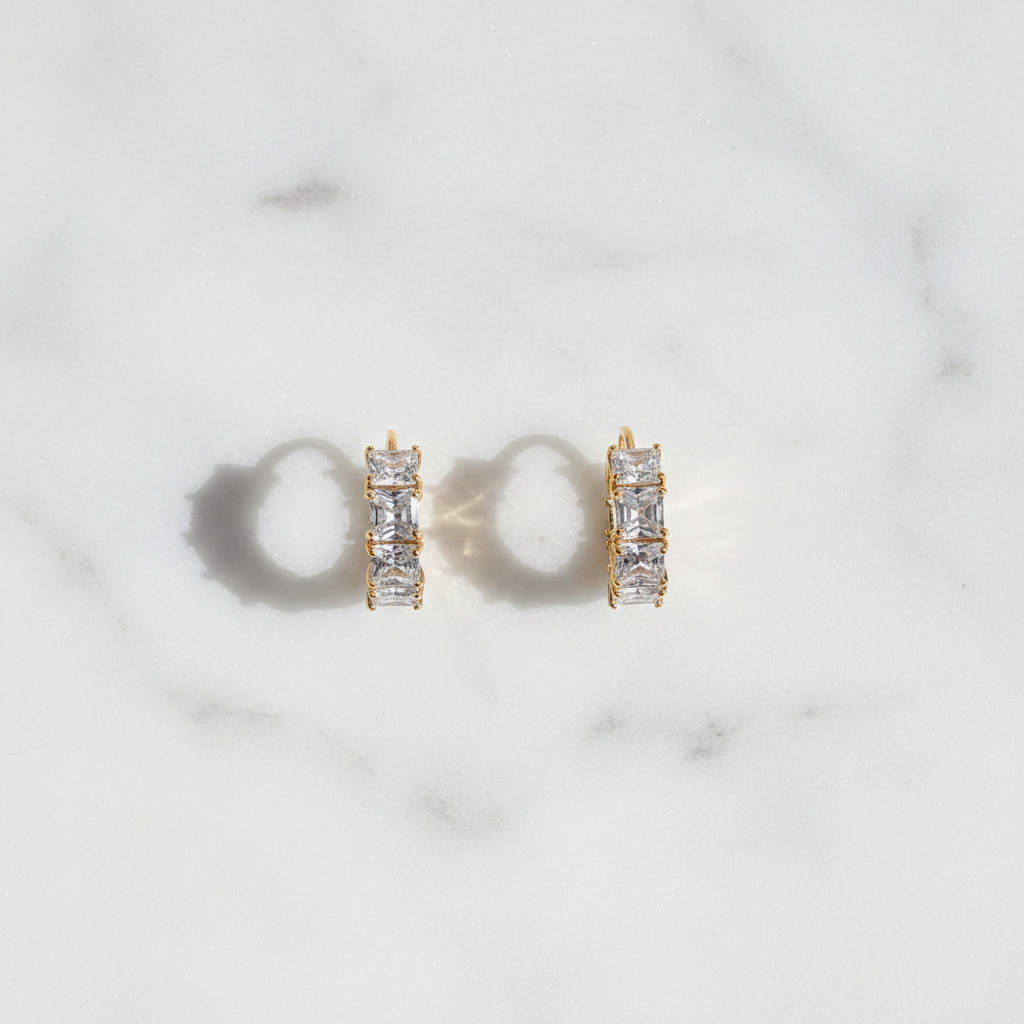 Kennedy white crystal stone huggie hoop earrings flat lay on white marble
