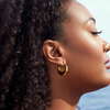 Dyani chunky gold crescent hoop earrings flat lay on white marble