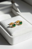 Élan emerald halo stud earrings on white velvet jewelry tray