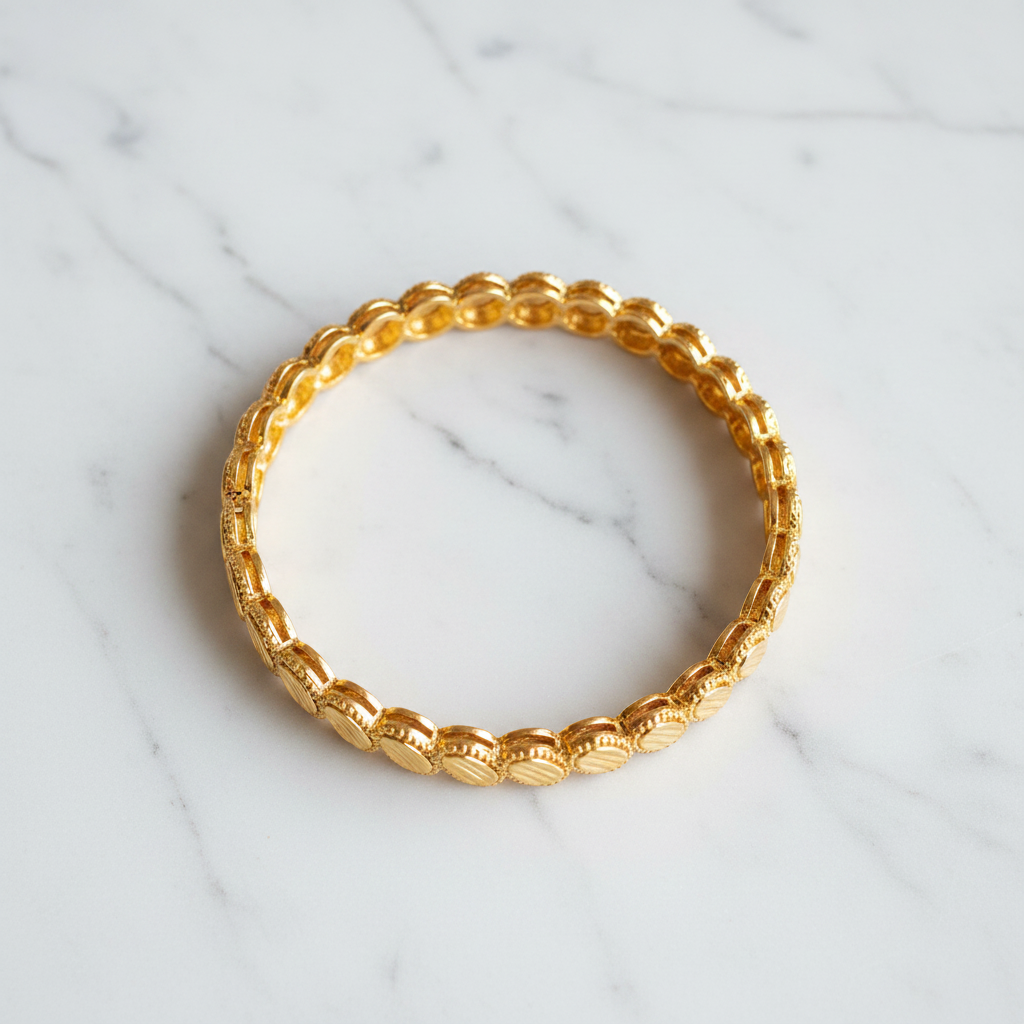 Ghana gold plated medallion bangle flat lay on white marble