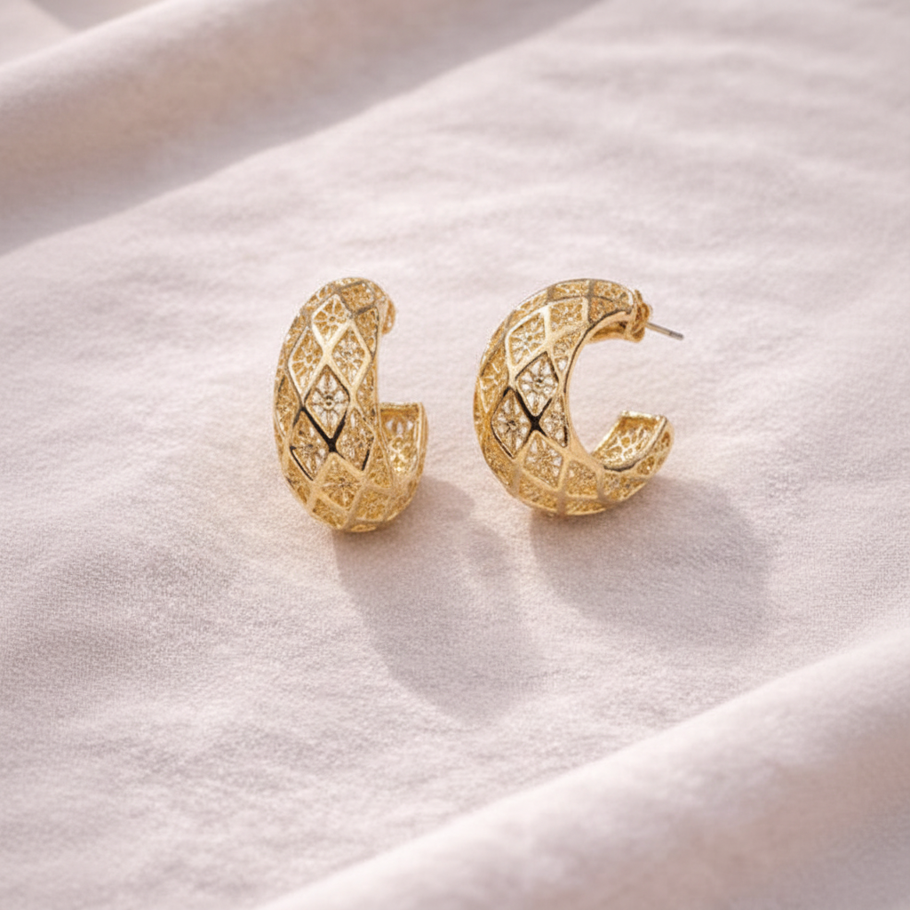 Ekow gold plated filigree semi hoop earrings flat lay on white linen