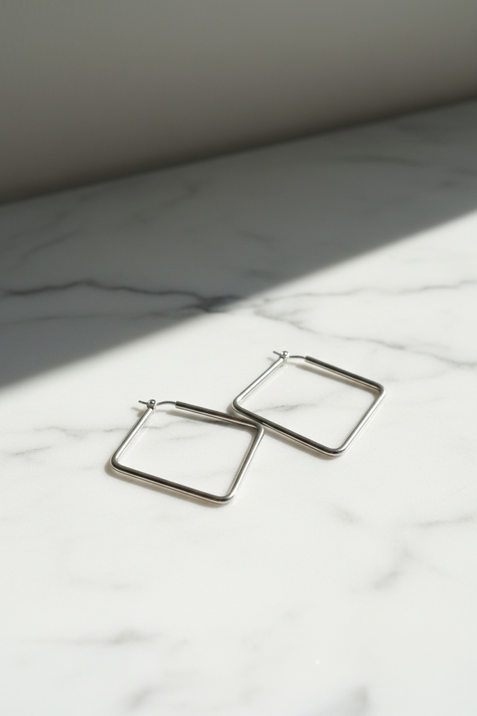 Merritt silver diamond rhombus geometric hoop earrings on marble with soft shadows