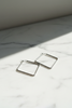 Merritt silver diamond rhombus geometric hoop earrings on marble with soft shadows