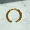 Liya textured beaded gold open cuff bracelet flat lay on white marble