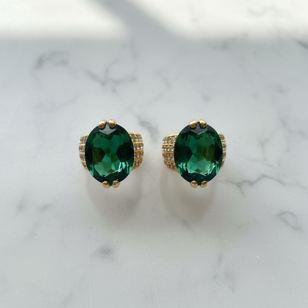 Marais emerald green oval gemstone huggie earrings flat lay on white marble