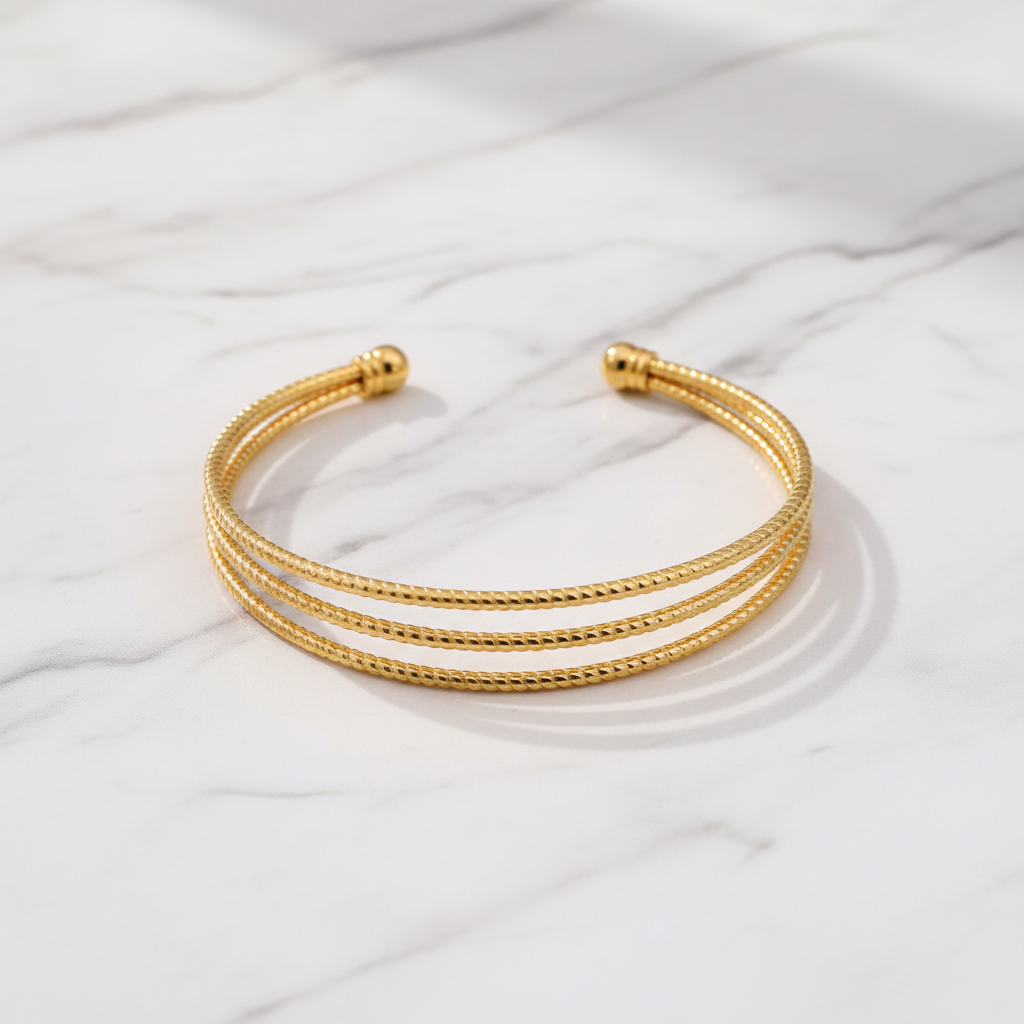 Bianca triple-row gold cuff bracelet flat lay on white marble