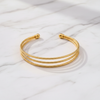 Bianca triple-row gold cuff bracelet flat lay on white marble