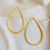 Bobbie gold oval hoop earrings flat lay on cream satin