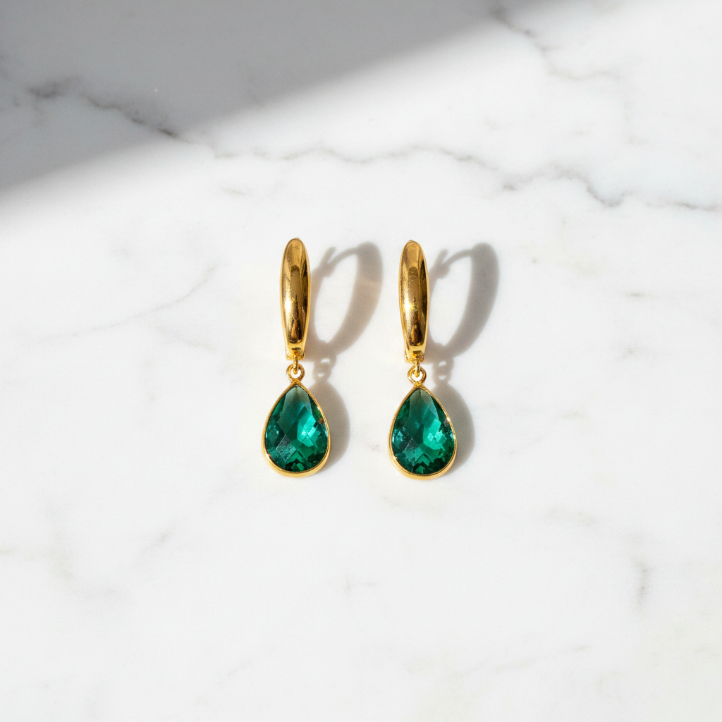 Amelia emerald green stone drop earrings flat lay on white marble