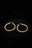 Efia gold twist hoop earrings on dark velvet jewelry tray