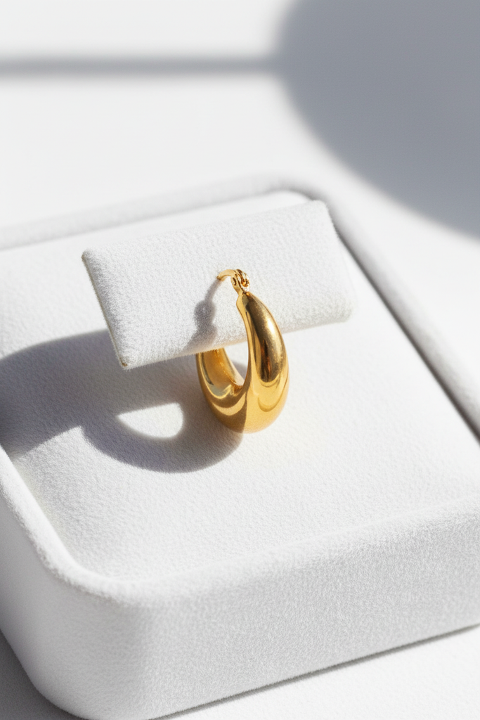 Dyani chunky gold crescent hoop earrings on white velvet jewelry tray