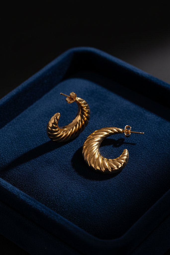Genet gold ribbed shrimp hoop earrings on dark velvet jewelry tray