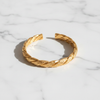 Tuscany gold twisted rope-and-braid cuff bracelet flat lay on white marble