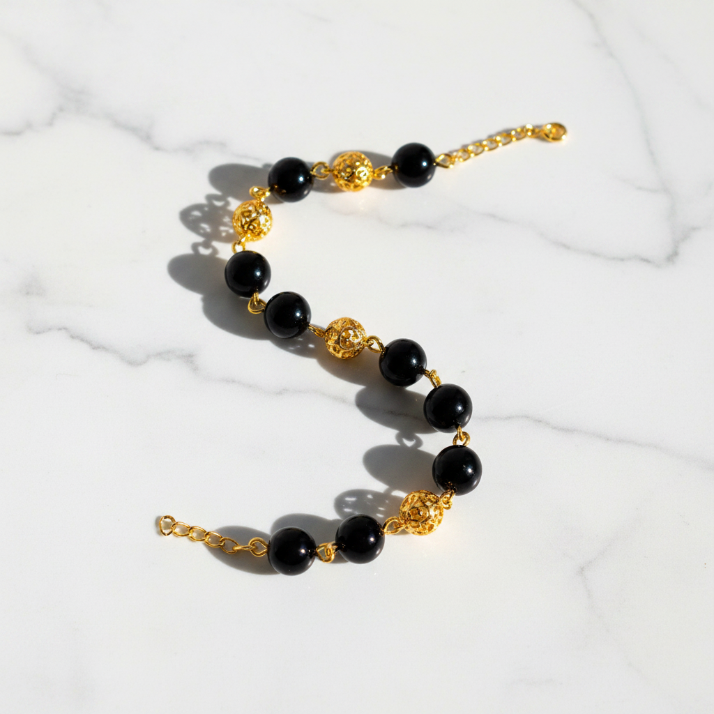 Elizabeth black resin and gold filigree ball bracelet flat lay on white marble