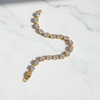 Winthrop tennis bracelet gold and white oval-cut stones flat lay on white marble