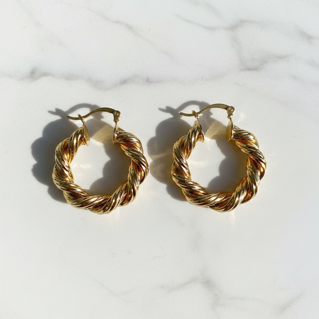 Twisted rope gold plated hoop earrings flat lay on white marble