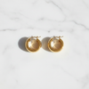 Aponi thick chunky gold stainless steel hoop earrings flat lay on white marble