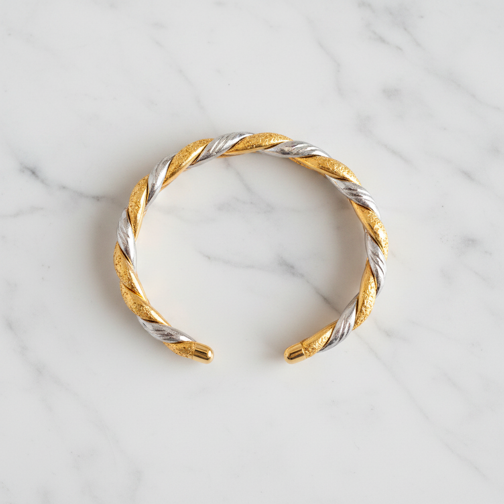 Tuscany two-tone gold and silver twisted rope-and-braid cuff bracelet flat lay on white marble