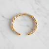 Tuscany two-tone gold and silver twisted rope-and-braid cuff bracelet flat lay on white marble