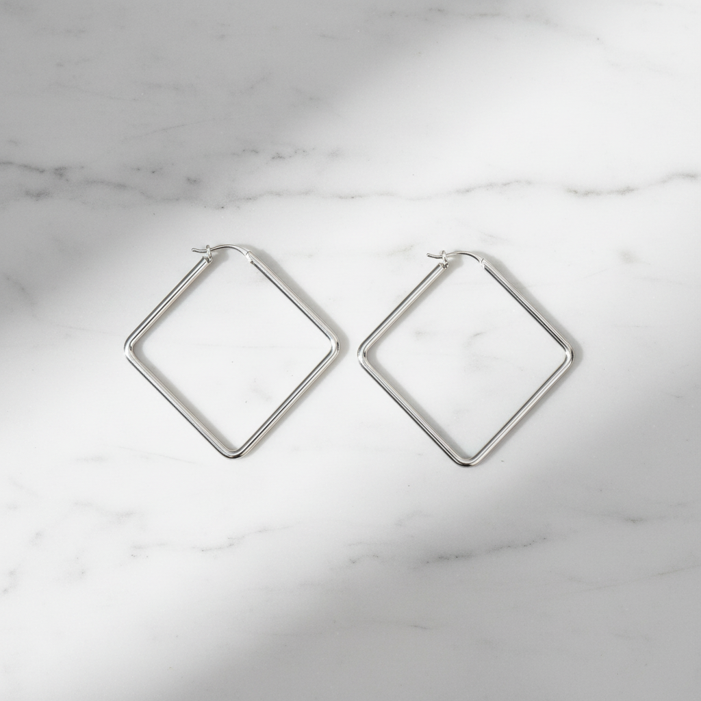 Merritt silver diamond rhombus geometric hoop earrings flat lay on white marble