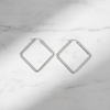 Merritt silver diamond rhombus geometric hoop earrings flat lay on white marble