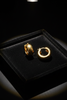 Aponi thick gold hoop earrings on dark velvet jewelry tray