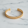 Isabella wide gold floral filigree open cuff bracelet flat lay on white marble